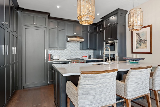 515 Church St Unit 3908, Nashville, TN 37219 - kitchen with a chandelier, dark wood-type flooring, under cabinet range hood, light countertops, and tasteful backsplash