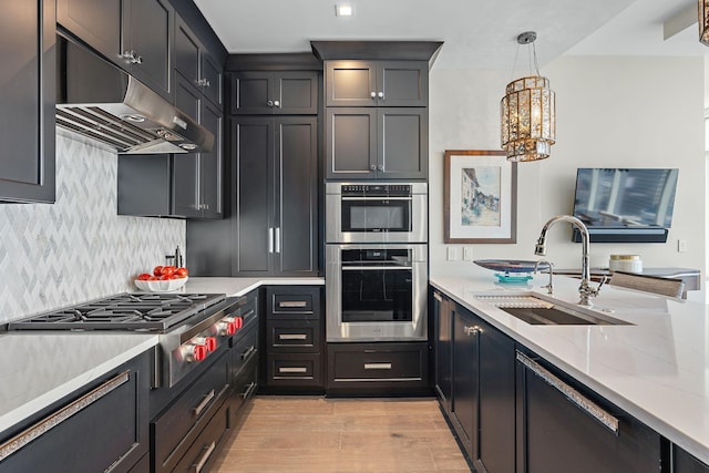 515 Church St Unit 3908, Nashville, TN 37219 - kitchen featuring stainless steel appliances, under cabinet range hood, a sink, decorative backsplash, and a chandelier