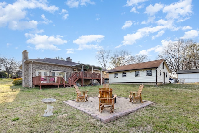 rear view of property with a patio, a chimney, an outdoor fire pit, a yard, and a deck