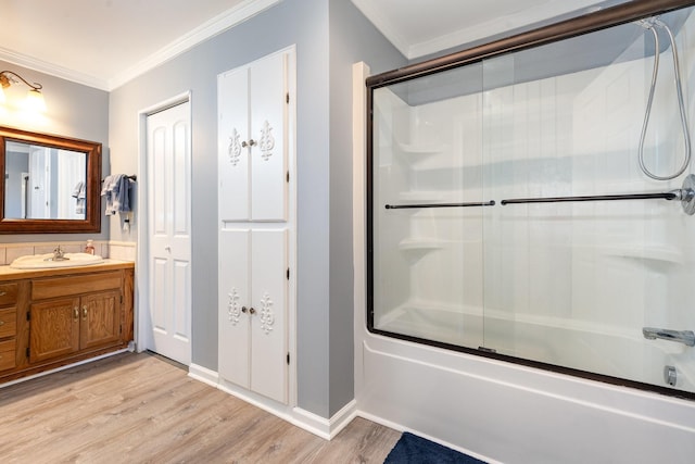 bathroom featuring vanity, ornamental molding, enclosed tub / shower combo, and wood finished floors