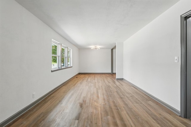 spare room featuring baseboards and wood finished floors