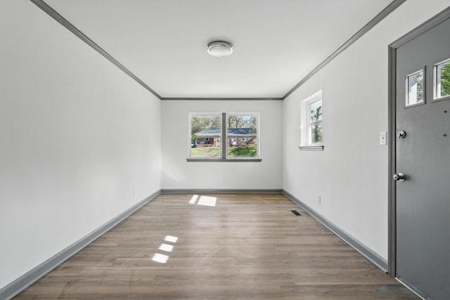 empty room featuring ornamental molding, wood finished floors, and baseboards