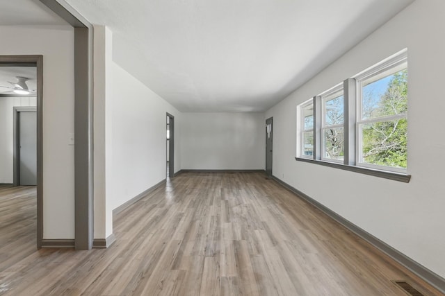 spare room featuring visible vents, light wood-type flooring, and baseboards