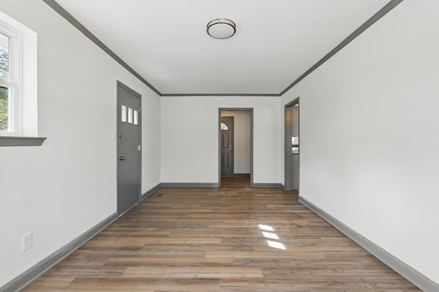 unfurnished room featuring crown molding, light wood-style flooring, and baseboards