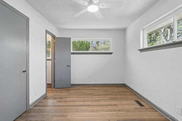 spare room with ceiling fan, visible vents, light wood-type flooring, and baseboards