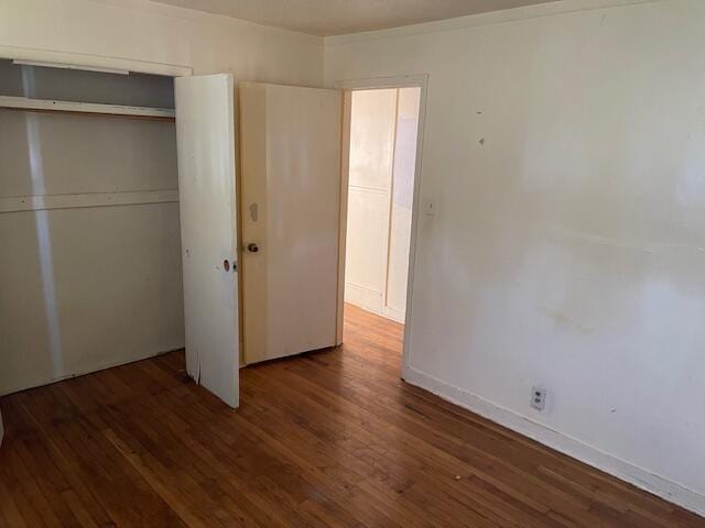 unfurnished bedroom featuring baseboards, a closet, and wood finished floors