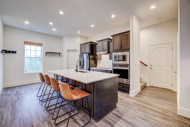 1006 Chisolm Trl, Goodlettsville, TN 37072 - kitchen with light countertops, light wood-type flooring, a breakfast bar, an island with sink, and appliances with stainless steel finishes