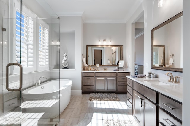 full bathroom featuring a shower stall, a freestanding bath, crown molding, and two vanities
