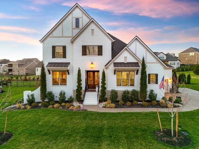 view of front of house featuring a standing seam roof, french doors, metal roof, and brick siding