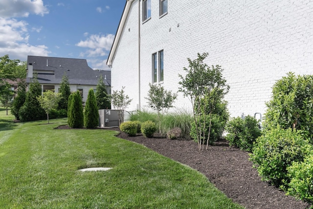 view of property exterior featuring a yard, brick siding, and central AC unit