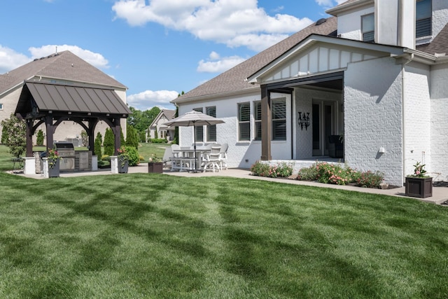 back of property featuring exterior kitchen, a gazebo, brick siding, and a yard