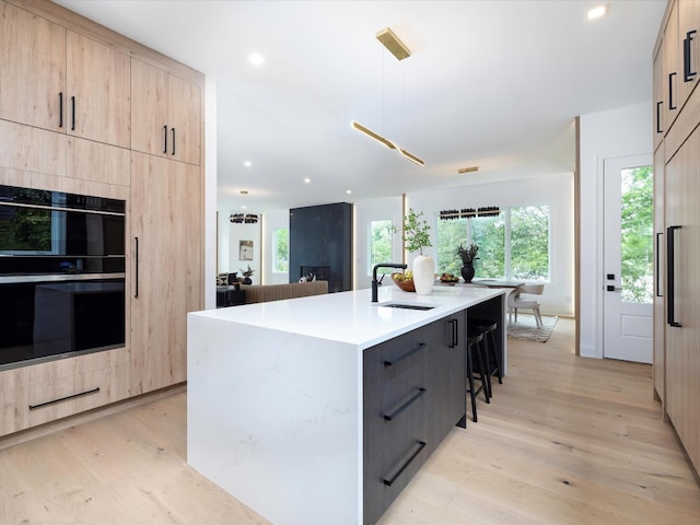 3848 Granny White Pike, Nashville, TN 37204 - kitchen featuring modern cabinets, light brown cabinetry, a sink, a kitchen bar, and light wood finished floors