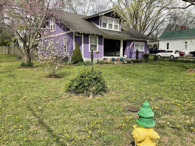 view of front of house with a front yard, fence, and a shingled roof