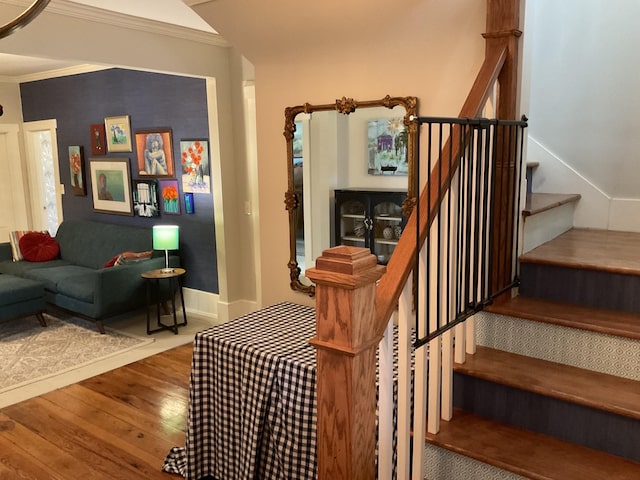 staircase featuring ornamental molding, wood-type flooring, and baseboards