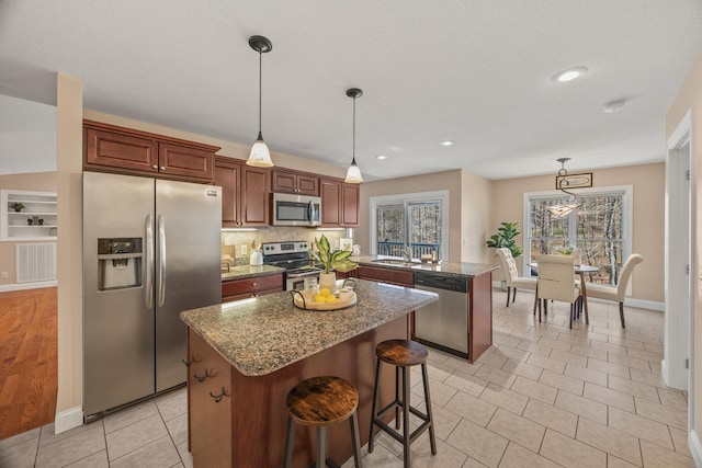 kitchen featuring visible vents, decorative light fixtures, appliances with stainless steel finishes, a peninsula, and a kitchen island