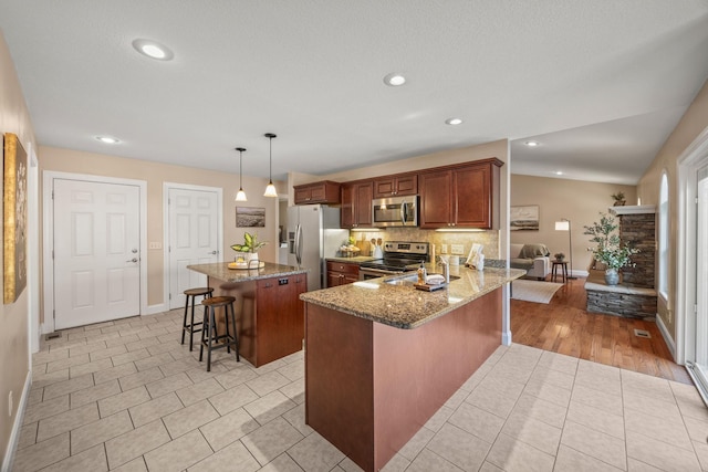 kitchen featuring stone countertops, a breakfast bar, baseboards, a kitchen island, and stainless steel appliances