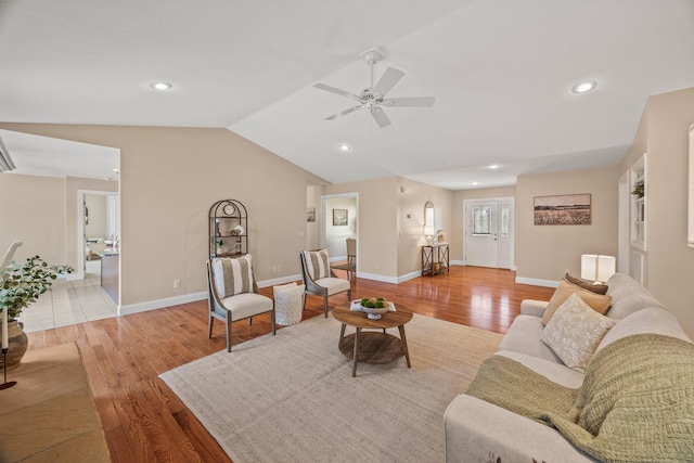 living area featuring light wood-style flooring, a ceiling fan, vaulted ceiling, and baseboards