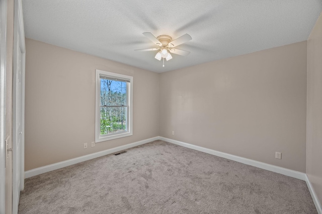 spare room featuring ceiling fan, a textured ceiling, visible vents, carpet flooring, and baseboards