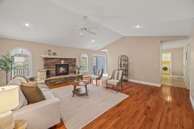 living area with lofted ceiling, washer / dryer, wood finished floors, a healthy amount of sunlight, and ceiling fan