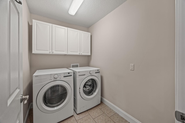 laundry room featuring baseboards, light tile patterned floors, a textured ceiling, cabinet space, and washer and dryer