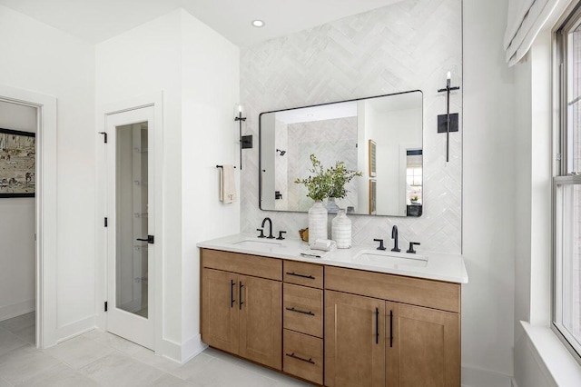 bathroom featuring a shower stall, double vanity, backsplash, and a sink