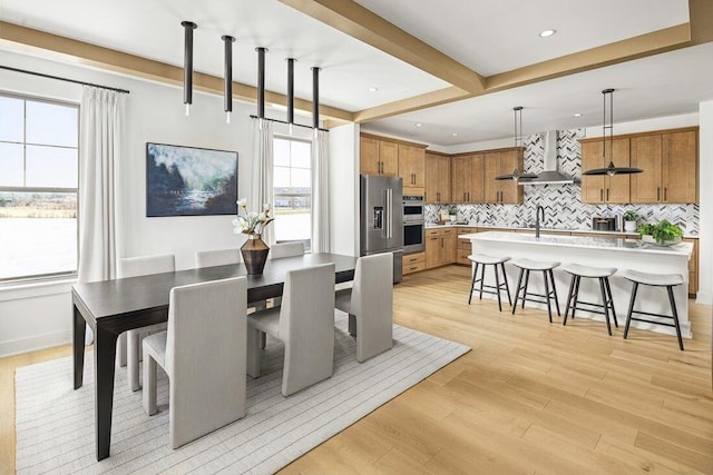 dining space featuring light wood-style floors, baseboards, beamed ceiling, and recessed lighting
