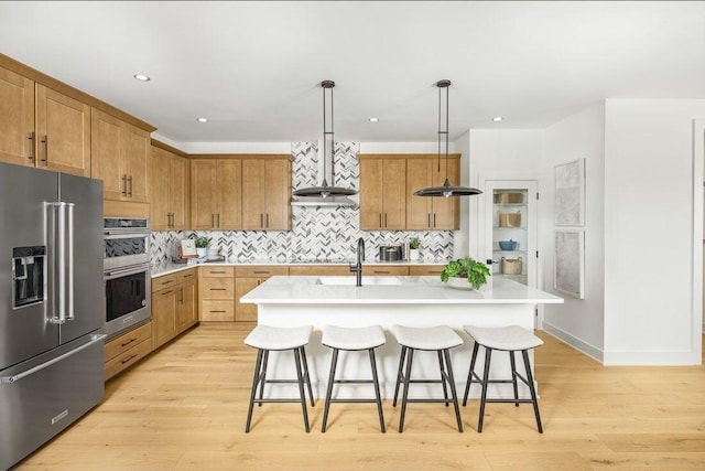 kitchen with light countertops, a sink, stainless steel appliances, and a breakfast bar
