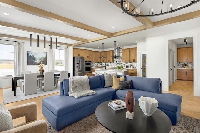 living area featuring light wood finished floors, beam ceiling, recessed lighting, and an inviting chandelier
