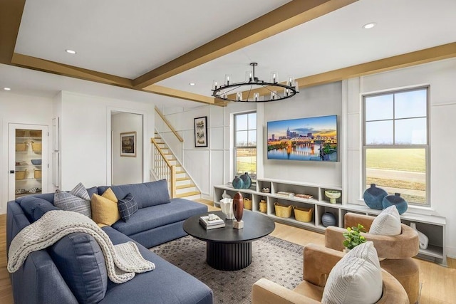 living room featuring stairs, wood finished floors, beam ceiling, and a chandelier