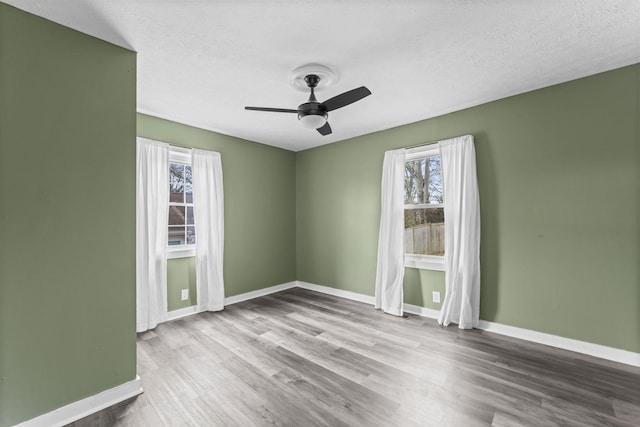 spare room featuring a ceiling fan, a textured ceiling, baseboards, and wood finished floors