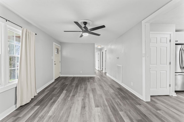unfurnished living room featuring visible vents, ceiling fan, wood finished floors, and a wealth of natural light