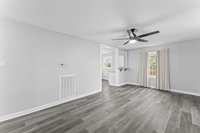 empty room featuring baseboards, dark wood-style floors, ceiling fan, and visible vents