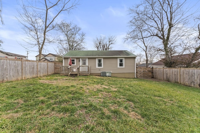 rear view of house with a fenced backyard, a lawn, a wooden deck, and central air condition unit
