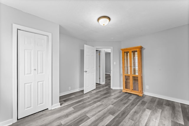 unfurnished bedroom featuring baseboards, a closet, and wood finished floors