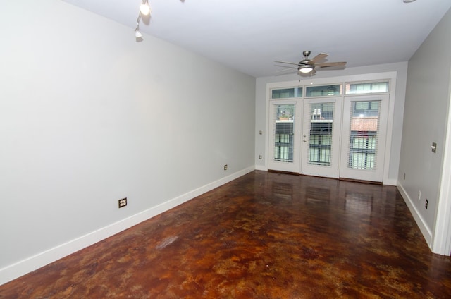 spare room featuring finished concrete floors, baseboards, and ceiling fan
