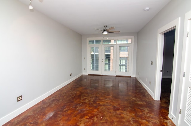 unfurnished room featuring finished concrete floors, baseboards, and ceiling fan