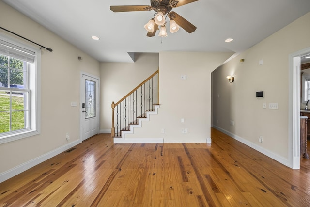 entryway with stairs, baseboards, hardwood / wood-style flooring, visible vents, and a ceiling fan