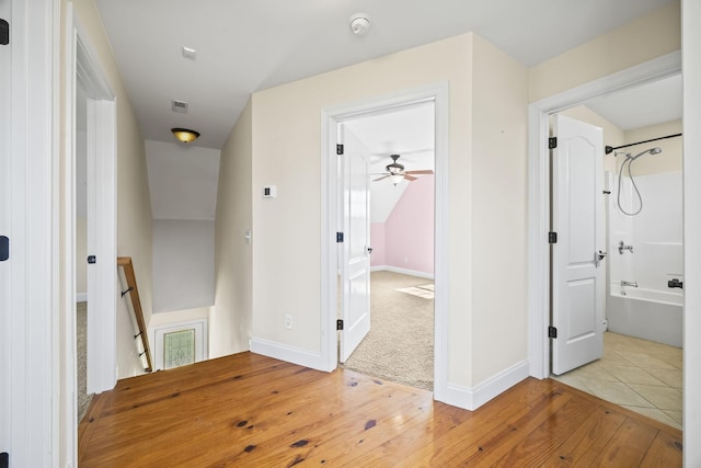 hallway featuring an upstairs landing, baseboards, light wood-style floors, and light colored carpet
