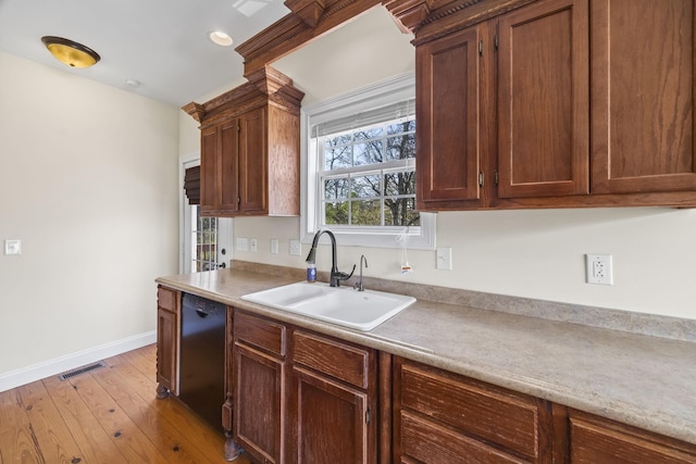 kitchen featuring baseboards, a sink, hardwood / wood-style flooring, visible vents, and dishwasher