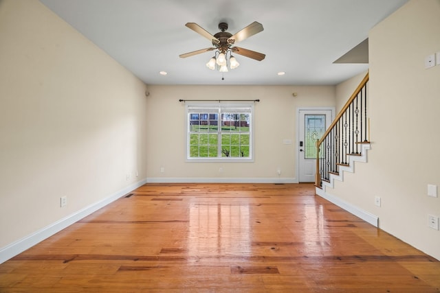 interior space with baseboards, light wood-style flooring, stairway, and a ceiling fan