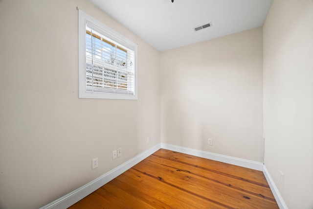 spare room with wood finished floors, baseboards, and visible vents