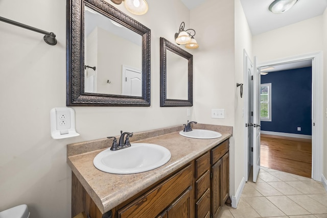 bathroom featuring baseboards, double vanity, a sink, and tile patterned flooring