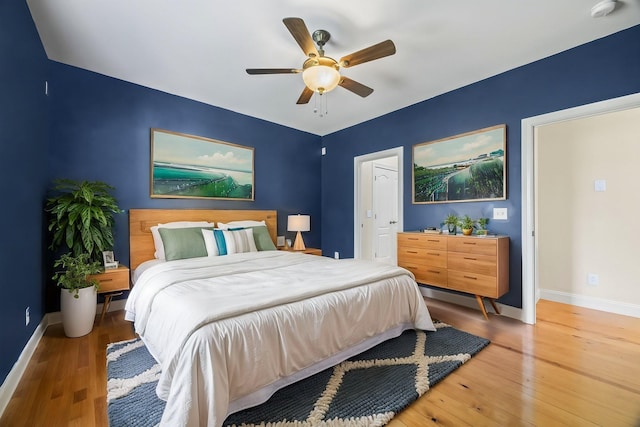 bedroom with hardwood / wood-style floors, a ceiling fan, and baseboards