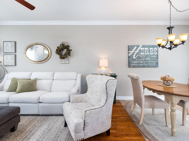 living area featuring dark wood-style floors, baseboards, ornamental molding, and ceiling fan with notable chandelier