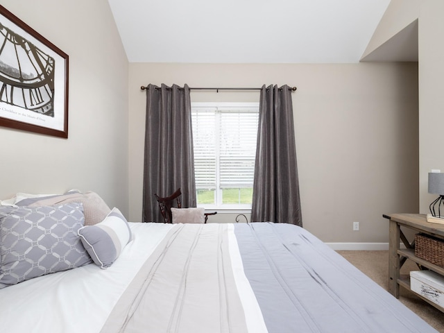 carpeted bedroom featuring baseboards and lofted ceiling