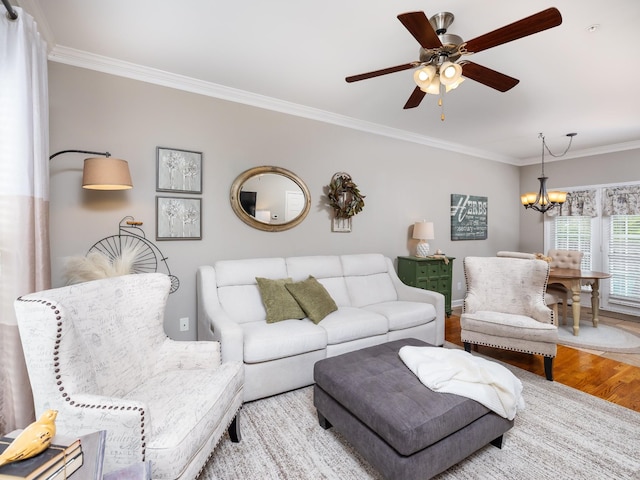 living room with wood finished floors, ceiling fan with notable chandelier, and ornamental molding