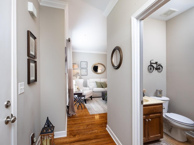 bathroom featuring visible vents, toilet, crown molding, vanity, and wood finished floors