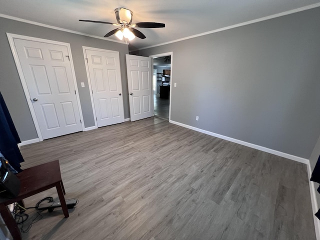 unfurnished bedroom featuring baseboards, multiple closets, and wood finished floors