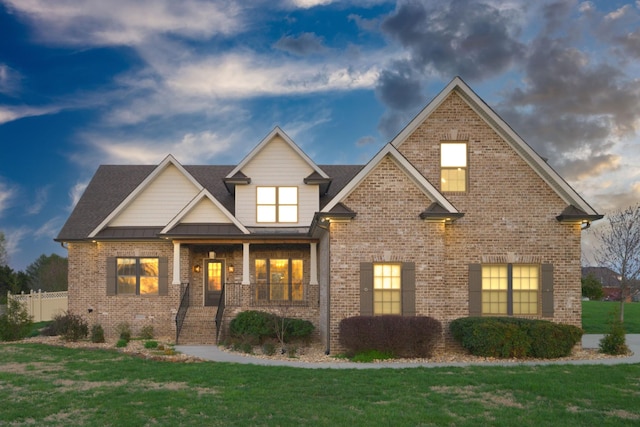 view of front of home with metal roof, fence, a front yard, brick siding, and a standing seam roof