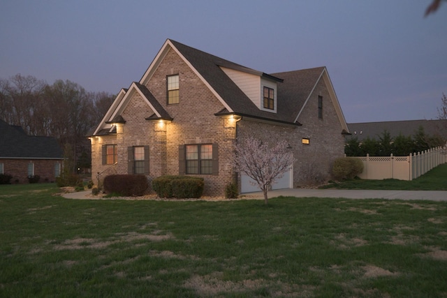view of front facade featuring fence, driveway, a front yard, brick siding, and a garage